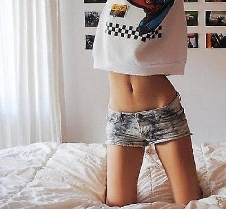 Девушка в майке и шортах на кровати