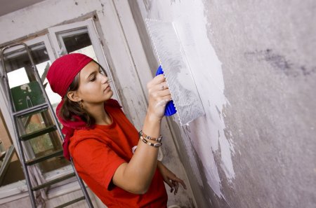 Женщина штукатурит стен