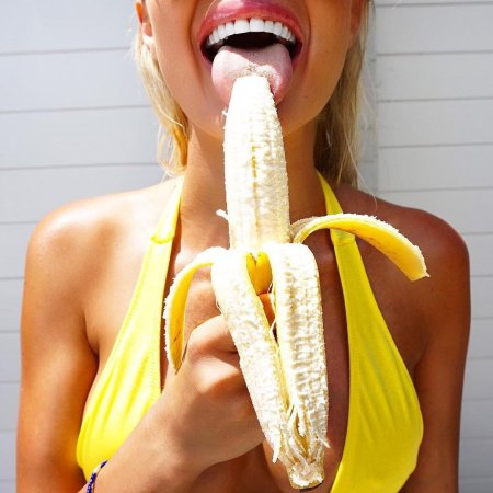 Красивая девушка ест банан