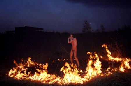 Naked man warms his Backside by a Campfire