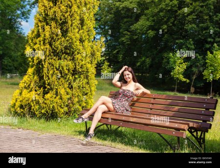 Девушка сидит на скамейке в парке