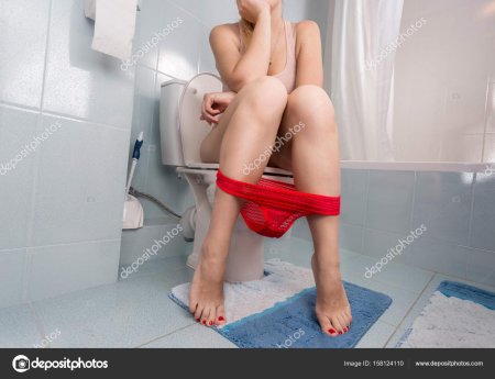 Женщина сидит на унитазе